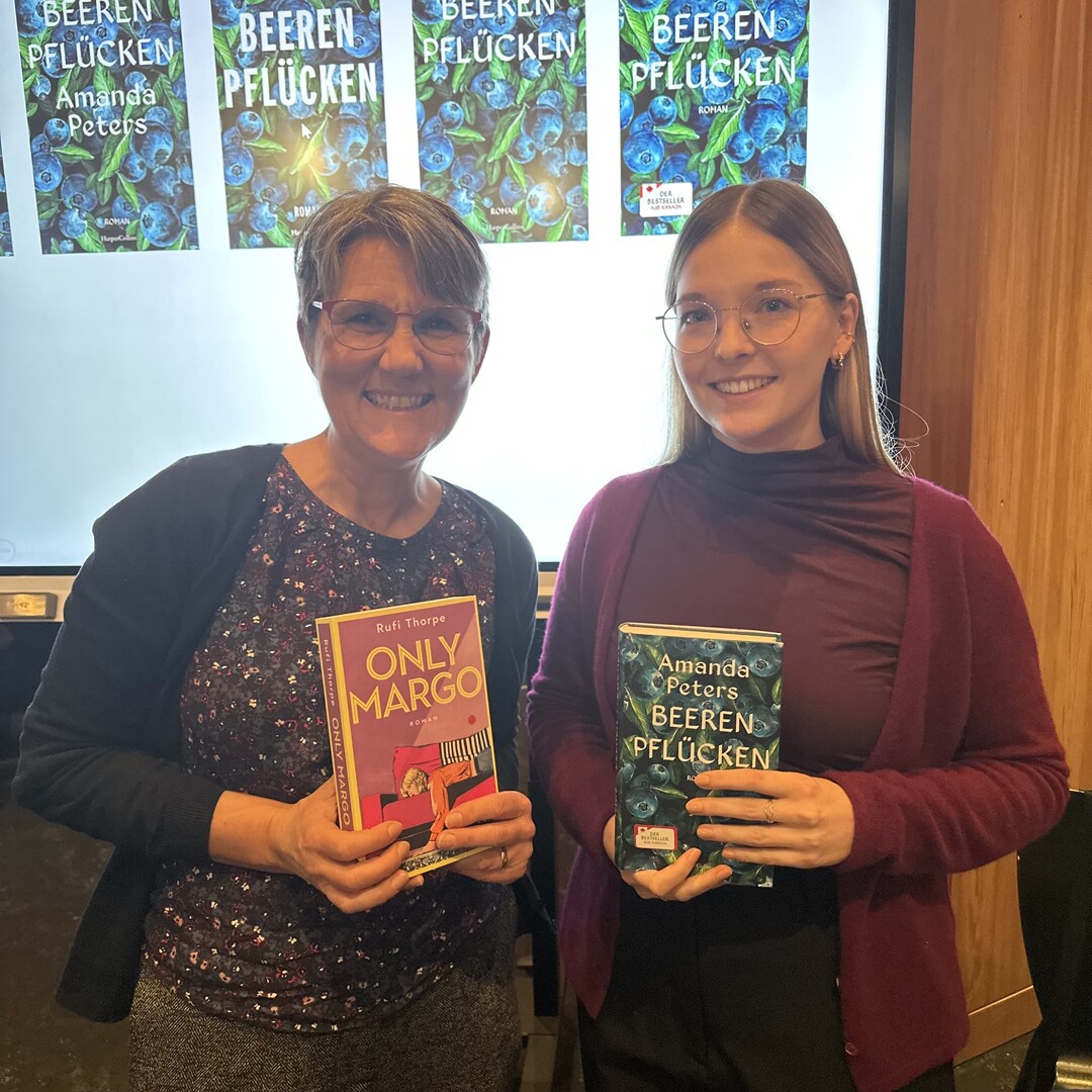 Frau Metzger und Frau K&ouml;rber vom Verlag Harper Collins halten die B&uuml;cher "Only Margo" und "Beeren pfl&uuml;cken" in die Kamera und l&auml;cheln.